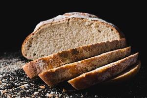 in Scheiben geschnittenes dunkles hausgemachtes Brot mit Mehl bestäubt foto