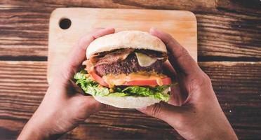 Hände halten einen verzehrfertigen Hamburger im Restaurant foto