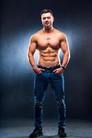 muskulös und passen jung Bodybuilder Fitness männlich Modell- posieren Über dunkel Hintergrund. foto