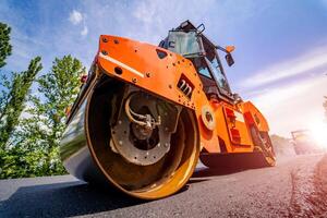 Straße Reparatur, Verdichter liegt Asphalt. schwer Besondere Maschinen. Asphalt Fertiger im Betrieb. Seite Sicht. Nahaufnahme. foto