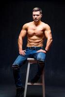 muskulös und passen jung Bodybuilder Fitness männlich Modell- posieren auf Stuhl. Studio Foto. voll Größe Porträt. foto