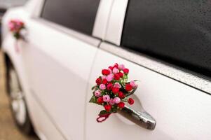 Hochzeit Auto mit schön Blume Dekorationen. Weiß Auto, rot Blumen, Hochzeit Tag, selektiv Fokus, Nahansicht foto