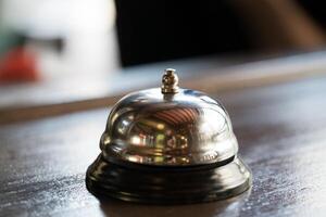 Glocke zum Anruf zum ein Bedienung von ein vergoldet Farbe steht auf ein hölzern Tabelle im das Restaurant. Nahansicht foto