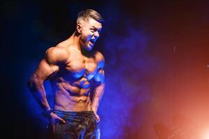 brutal stark sportlich Männer Pumpen oben Muskeln. trainieren und Bodybuilding Konzept. Blau Licht Filter. gut aussehend Mann mit nackt Torso. Fitness Modell- ist posieren. foto