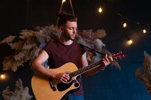 männlich Musiker spielen akustisch Gitarre. Gitarrist Theaterstücke klassisch Gitarre auf Bühne im Konzert foto