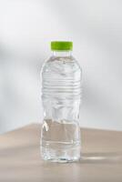 Trinken Wasser im Plastik Flaschen auf ein hölzern Tabelle unter das Morgen Sonnenlicht. foto