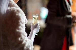 stilvoll Braut hält Glas mit Champagner im Hände. verschwommen Hintergrund. selektiv Fokus. Hochzeit Tag. foto