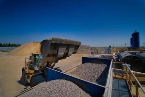 Wagen auf Wird geladen mit zerquetscht Stein. Transport von Bulk Materialien. Werdegang oder Steinbruch foto