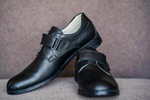 schwarz Leder Schuhe zum Junge. klassisch Jungs Kinder- Neu schwarz Schule Schuhe auf grau Hintergrund. foto