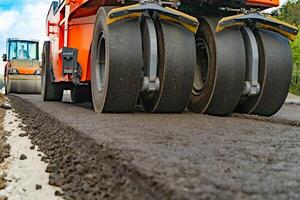 Asphalt Walze Das Stapel und Drücken Sie heiß Asphalt während Herstellung ein Neu Straße. Straße Reparatur Maschine mit schwer Vibration Walzen Verdichter foto