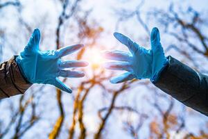 Hände im Blau medizinisch Handschuhe auf das Straße vermeiden das Verbreitung von Coronavirus. Pandemie COVID-19. halt Coronavirus foto