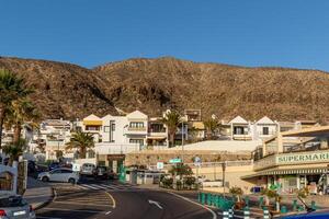 urig Küsten Stadt, Dorf mit Weiß Gebäude eingebettet gegen Hügel unter ein klar Blau Himmel im los Cristianos, Teneriffa. foto