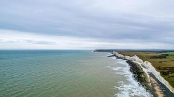 Antenne Aussicht von ein Kreide Cliff Küste mit Grün Felder unter ein wolkig Himmel. foto