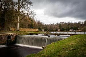 still Fluss Szene mit ein glatt Wasserfall, bedeckt Himmel, und üppig Grün, Ideal zum heiter Landschaft Themen. foto