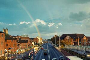 städtisch Landschaft mit Regenbogen Über Stadt Straße und historisch Gebäude beim Sonnenuntergang. foto