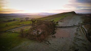 Antenne Aussicht von ein still Landschaft beim Sonnenuntergang mit rollen Hügel, Wicklung Straßen, und ein warm, glühend Himmel beim Bergahorn Lücke, Northumberland, Vereinigtes Königreich. foto