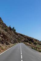 leeren Straße Dehnen durch ein felsig Landschaft unter ein klar Blau Himmel im Teneriffa. foto