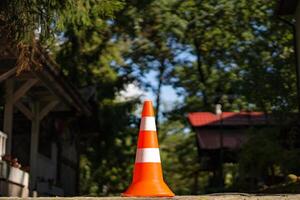 Straße Kegel von zwei Farben mit Orange und Weiß Stehen Über das natürlich Hintergrund. Warnung gestreift Plastik Orange Parkplatz Kegel in der Nähe von das Häuser im Wald. foto