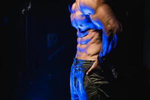 brutal stark sportlich Männer Pumpen oben Muskeln. trainieren und Bodybuilding Konzept. schwarz und Blau Licht Hintergrund. gut aussehend Mann mit nackt Torso. Fitness Modell- ist posieren. foto