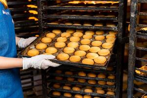 Mädchen im Uniform Arbeiten mit frisch Bäckerei. Backen Beruf Arbeitsplatz. foto