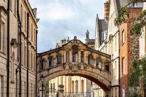 historisch Stein Brücke verbinden zwei alt Gebäude gegen ein wolkig Himmel im Oxford, England. foto