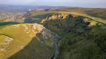 Antenne Aussicht von ein Wicklung Straße durch üppig Grün Hügel mit felsig Aufschlüsse unter ein klar Himmel im Gipfel Bezirk, England. foto