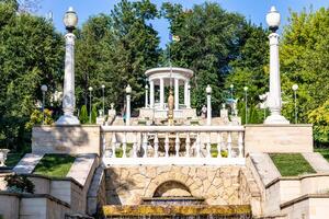 elegant Garten Pavillon mit Balustraden und Schritte umgeben durch üppig Grün und klar Blau Himmel im Chișinău, Moldawien. foto