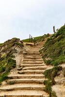 rustikal hölzern Treppe aufsteigend ein grasig Hang, führen zu ein bedeckt Himmel, Konzept von Reise und Aufstieg. foto