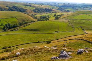 rollen Grün Hügel mit Patchwork Felder und Stein Wände, abbilden ländlich Landschaft Landschaft. foto