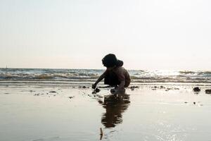 wenig asiatisch Junge spielen im das Sand beim das Meer Strand foto