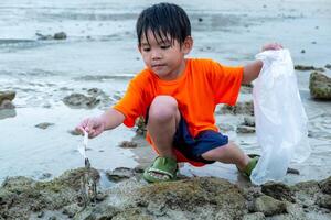 wenig asiatisch Junge fängt Krabben auf das Meer Strand foto