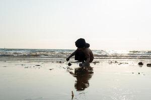 wenig asiatisch Junge spielen im das Sand beim das Meer Strand foto