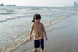 wenig asiatisch Junge spielen im das Sand beim das Meer Strand foto