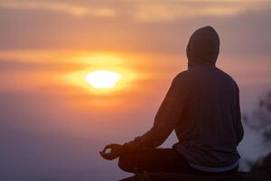zurück Aussicht von Mann ist entspannend üben Meditation Yoga Mudra beim Berg oben mit Sonnenaufgang im Winter zu erreichen Glück von innere Frieden Weisheit zum gesund Verstand und Seele foto