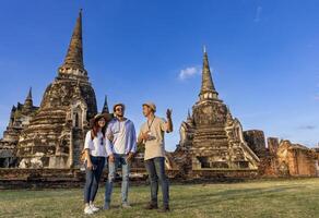 thailändisch lokal Tour leiten ist erklären das Geschichte von alt Siam zu das Paar von Tourist auf ihr Backpacker Flitterwochen Reise zu uralt Tempel von Ayutthaya, Thailand foto