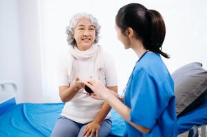Arzt im Weiß passen nehmen Anmerkungen während diskutieren und asiatisch Alten, Frau geduldig Wer Lügen auf Bett mit Empfang Kochsalzlösung Lösung foto