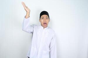 asiatisch Mann Muslim erziehen Hand zu präsentieren etwas über mit Schock Gesicht Ausdruck isoliert auf Weiß Hintergrund foto