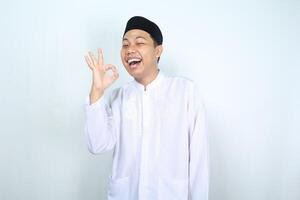 froh asiatisch Muslim Mann Show in Ordnung Zeichen mit Lachen Ausdruck isoliert auf Weiß Hintergrund foto
