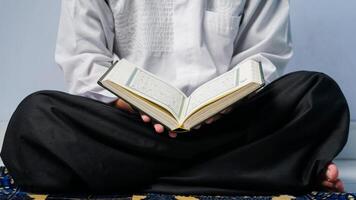 schließen oben von ein Muslim Mann Sitzung beten und lesen das Koran auf ein Gebet Matte. foto