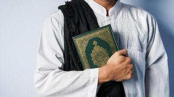 ein Muslim Mann trägt das Koran im beide Hände. Konzept von das Monat von Ramadan foto