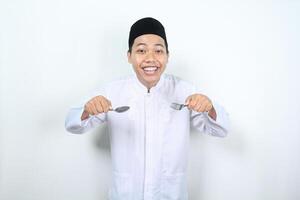 Muslim asiatisch Mann lächelnd glücklich halten Löffel und Gabel Show bereit zu Essen Geste isoliert foto