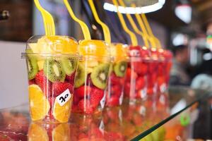 Ananas, Kiwi und Erdbeeren In. Plastik Container Verkauf beim Geschäft foto