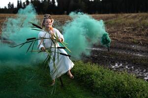 heiter jung Frau mit Schilf Tänze im farbig Rauch im ein Feld foto