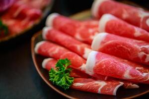 geschnitten Oberseite wagyu Rindfleisch zum Yakiniku auf Teller auf schwarz Hintergrund, Prämie japanisch Fleisch foto