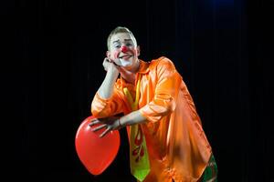 Zirkus Clown führt aus Nummer. ein Mann im ein Clown Outfit mit ein Spielzeug.a Mann im ein Clown Outfit mit ein Ballon foto