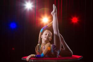 ein Mädchen mit ein flexibel Körper. führt aus ein Zirkus Künstler. Zirkus Turner. balancieren Gesetz. das Kind führt aus ein akrobatisch Trick foto