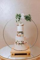 ein dreistufig Hochzeit Kuchen dekoriert mit Blumen steht auf ein gespiegelt Tisch. dekorativ Hochzeit Kuchen. Schönheit ist im das Einzelheiten. foto