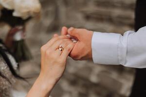 Bräutigam halten Braut Hand, abgeschnitten Foto. Einzelheiten beim das Hochzeit. Gold Hochzeit Ringe auf Hände. hoch Qualität Foto. foto