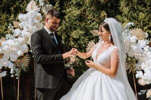 Hochzeit Zeremonie im Natur. das Braut und Bräutigam in der Nähe von das Blume Bogen. das Moderator beim das Hochzeit während das Rede. foto