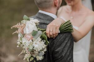 das Braut und Bräutigam umarmen. das Braut sanft Umarmungen das Bräutigam durch das Schultern. schön Hochzeit Paar. das Konzept von Romantik im ein Jungvermählten Beziehung. Flitterwochen. foto